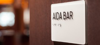 Schild mit Brailleschrift AIDA Bar